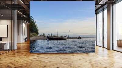 wooden boat with deer`s head in the harbor in the delta of Chornaya river near cape Besov Nos, Onega lake, Russia. Blue sky with clouds and dark blue water Wall mural